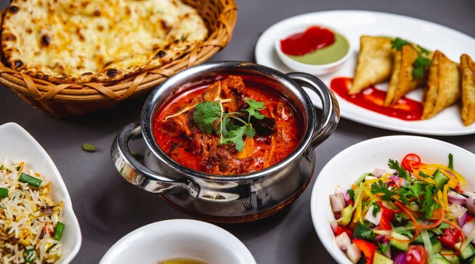 A vibrant Indian feast with naan, curry, samosas, fried rice, and a fresh salad.